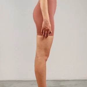 Giovane modella di profilo indossa ciclista per Pilates Infinity, color cipria chic, della linea di abbigliamento Be You Firenze