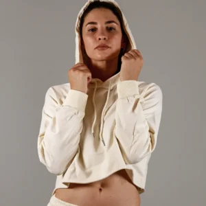 Giovane modella indossa felpa Crop con cappuccio alzato per Pilates, color burro, modello Akira, della linea di abbigliamento Be You