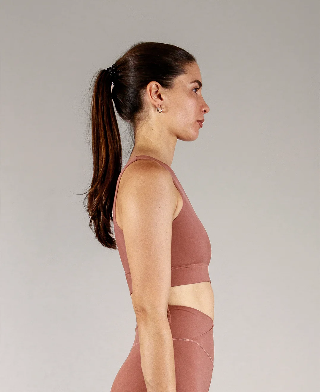 Giovane modella indossa top per Pilates Infinity, color cipria chic, della linea di abbigliamento Be You Firenze