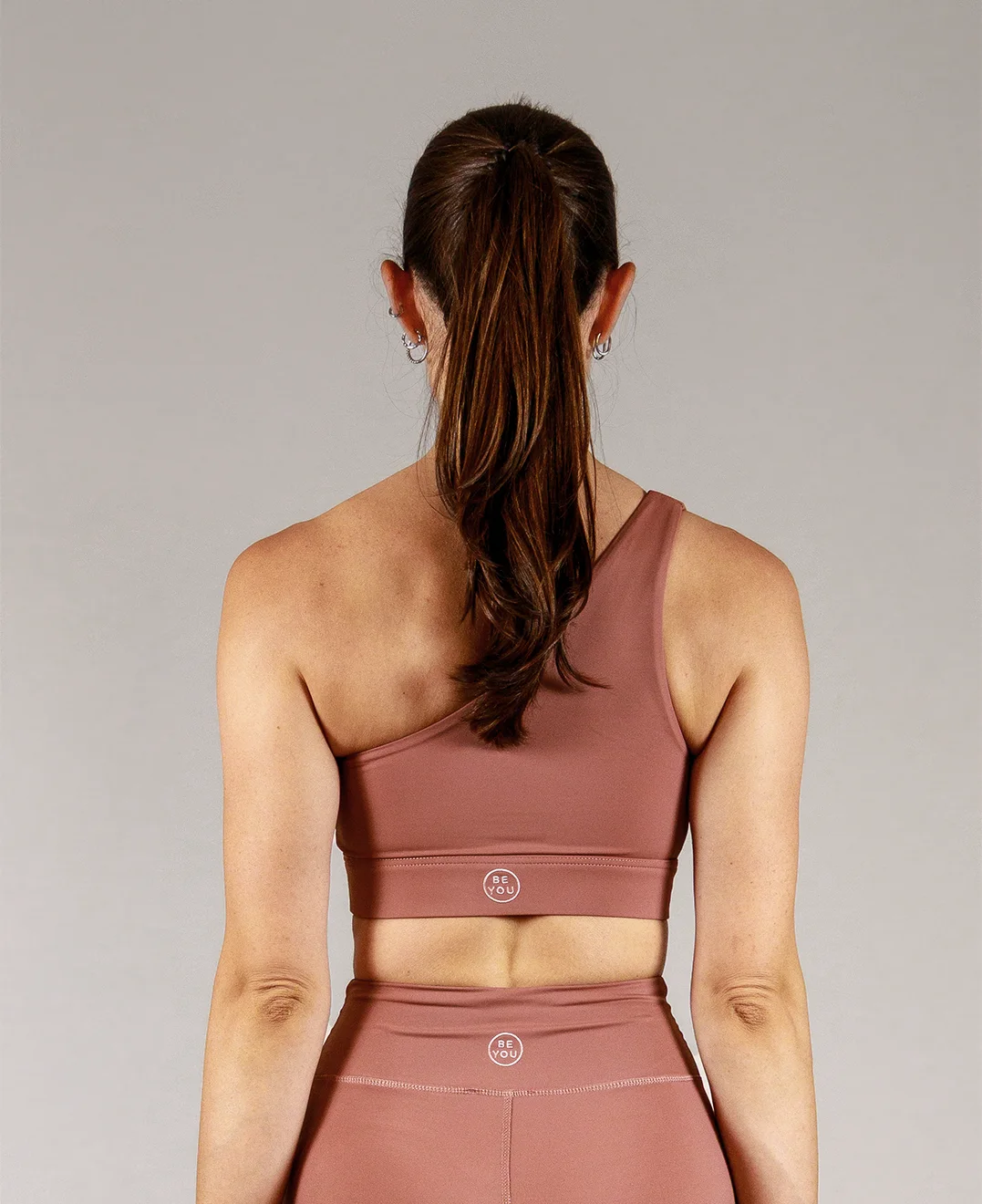 Giovane modella indossa top per Pilates Infinity, color cipria chic, della linea di abbigliamento Be You Firenze